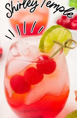close up shot of a glass of Shirley Temple garnished with cherries and a lime slice