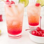 close up shot of glasses of Shirley Temple garnished with cherries and lime slices