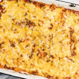 Overhead view of a large baked sloppy joe casserole in a white rectangular dish, topped with golden melted cheese.