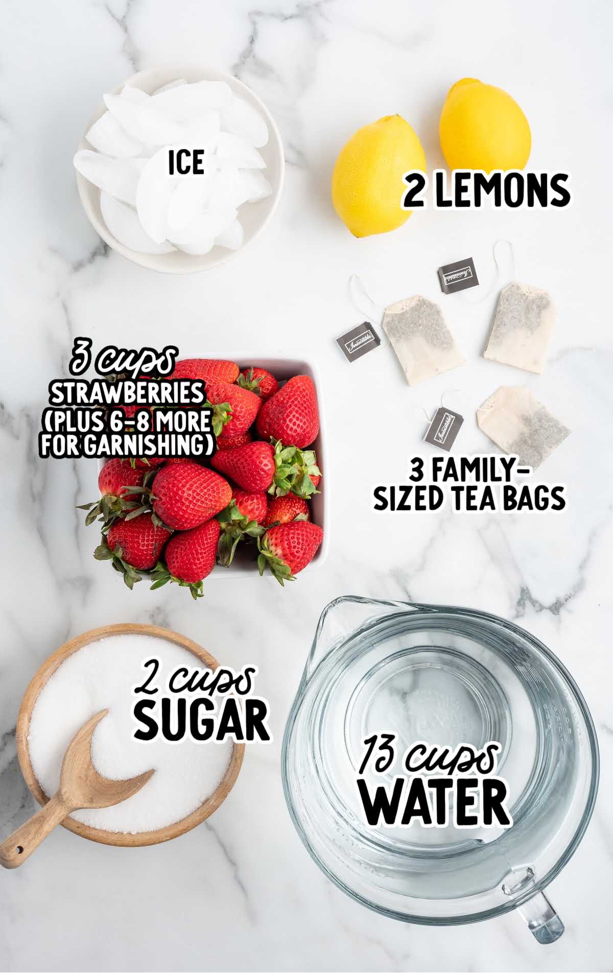 Flat lay of sweet tea ingredients including lemons, strawberries, sugar, tea bags, ice, and a pitcher of water.