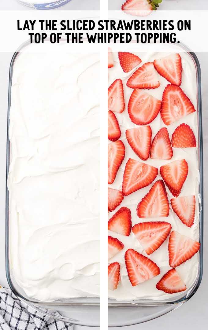 strawberry poke cake process shot of cake being topped with whipped cream and strawberry slices