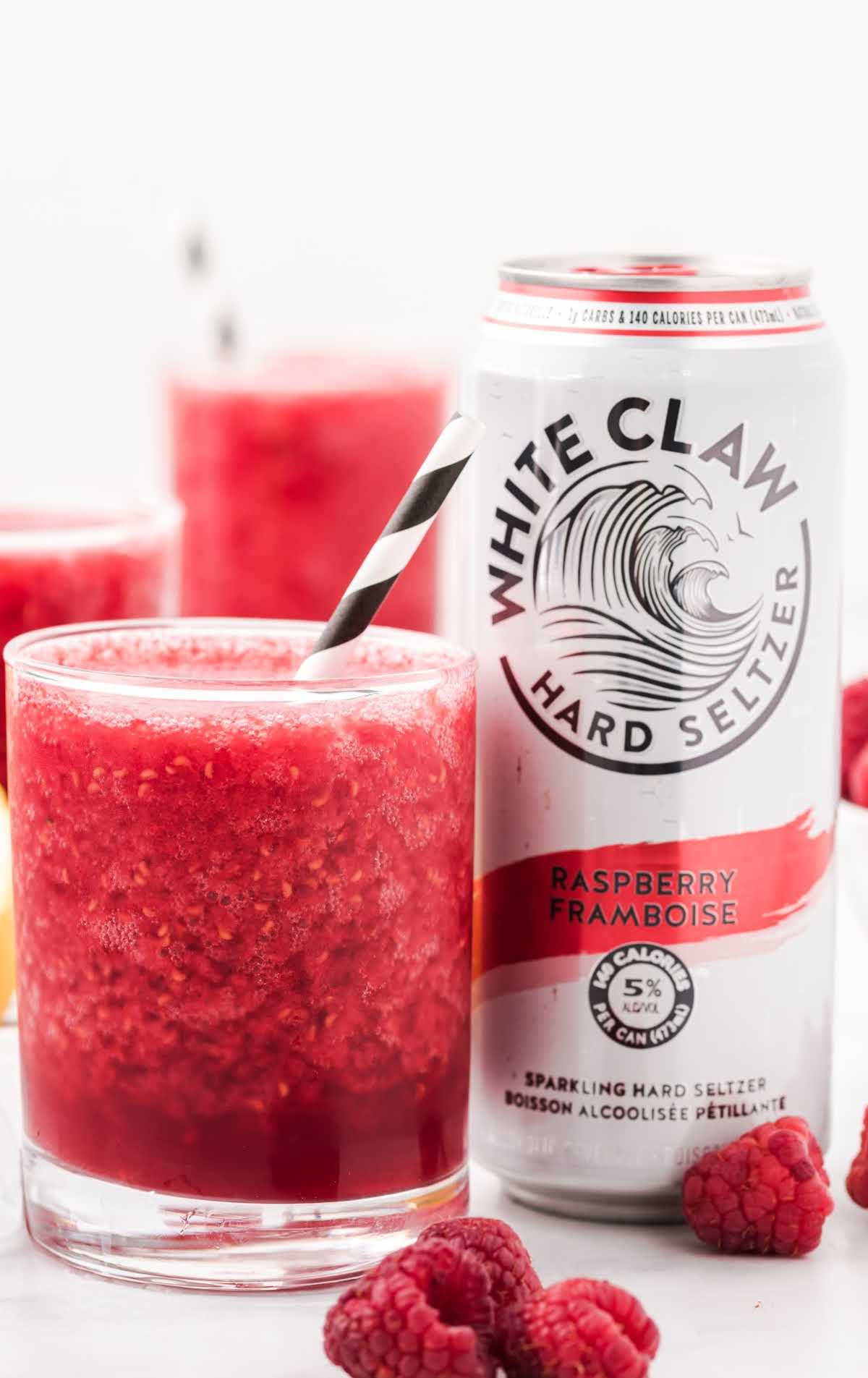 close up shot of White Claw slushie in a glass cup with a straw and a can of white claw
