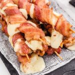 close up shot of bacon-wrapped mozzarella sticks on a piece of paper