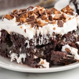 Close-up of a forkful taken out of a slice of better than sex cake showing moist chocolate layers, caramel, and whipped topping.