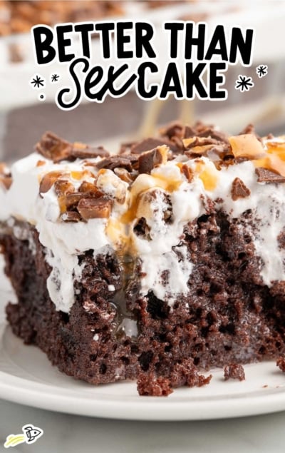 Side view of better than sex cake slice with layers of chocolate cake, caramel sauce, whipped cream, and Heath bar pieces.