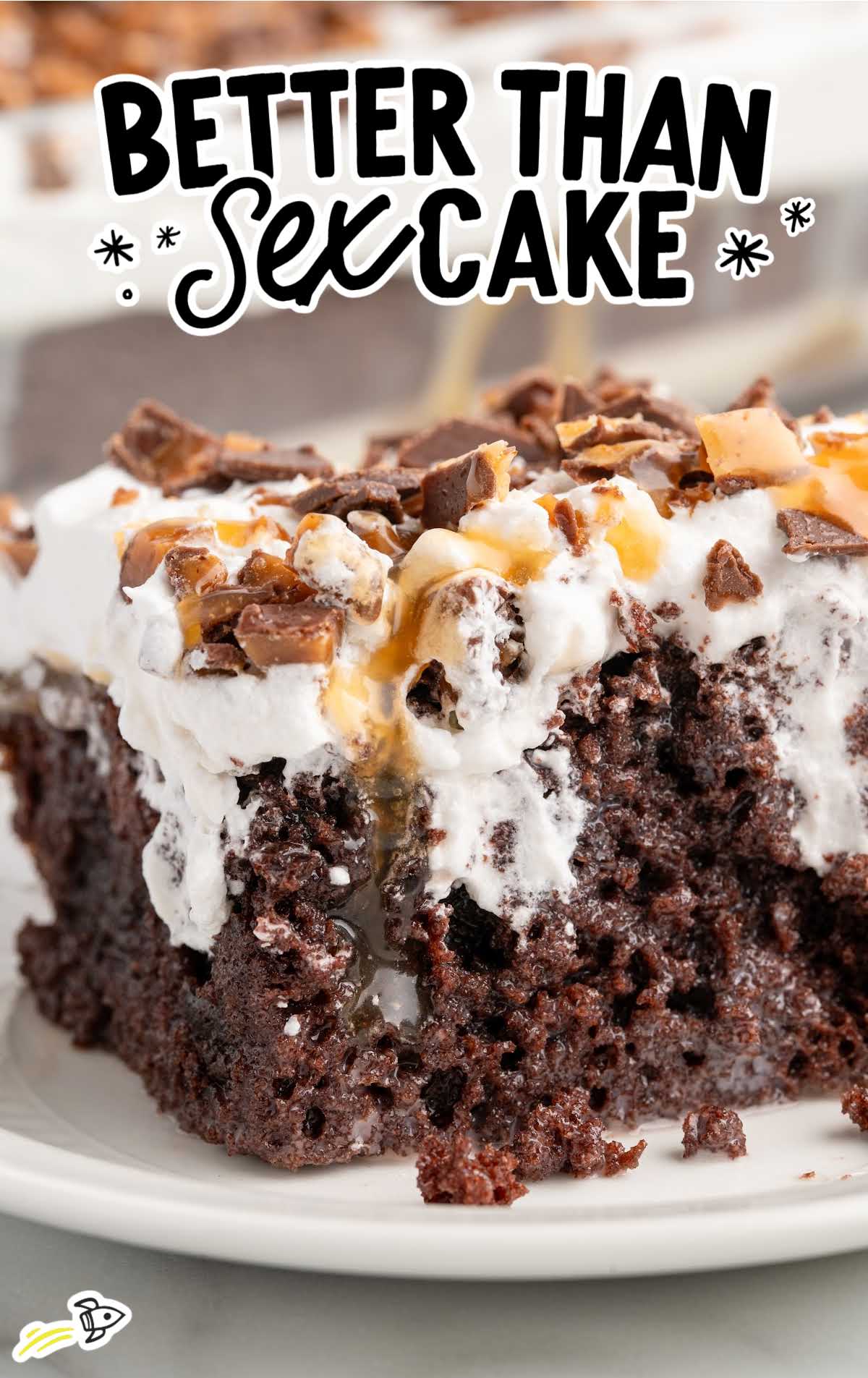 Side view of better than sex cake slice with layers of chocolate cake, caramel sauce, whipped cream, and Heath bar pieces.