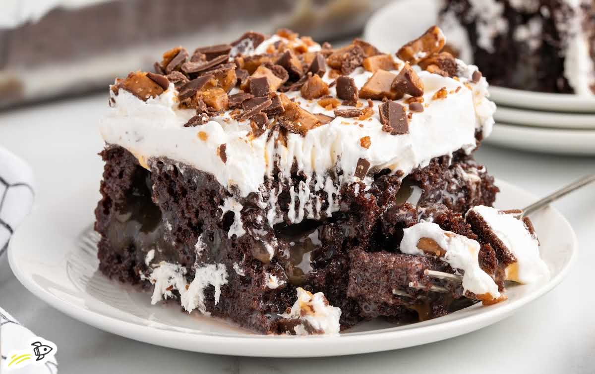 Fork cutting into a slice of better than sex cake with gooey caramel filling and fluffy whipped topping.