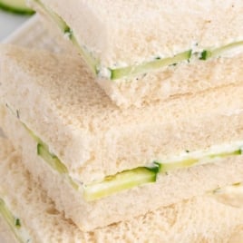 Stack of cucumber tea sandwiches made with white bread, cream cheese spread, and cucumber slices, labeled "The Best Ever Cucumber Tea Sandwiches."
