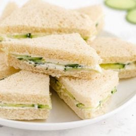 close up shot of cucumber sandwiches piled on top of each other on a plate