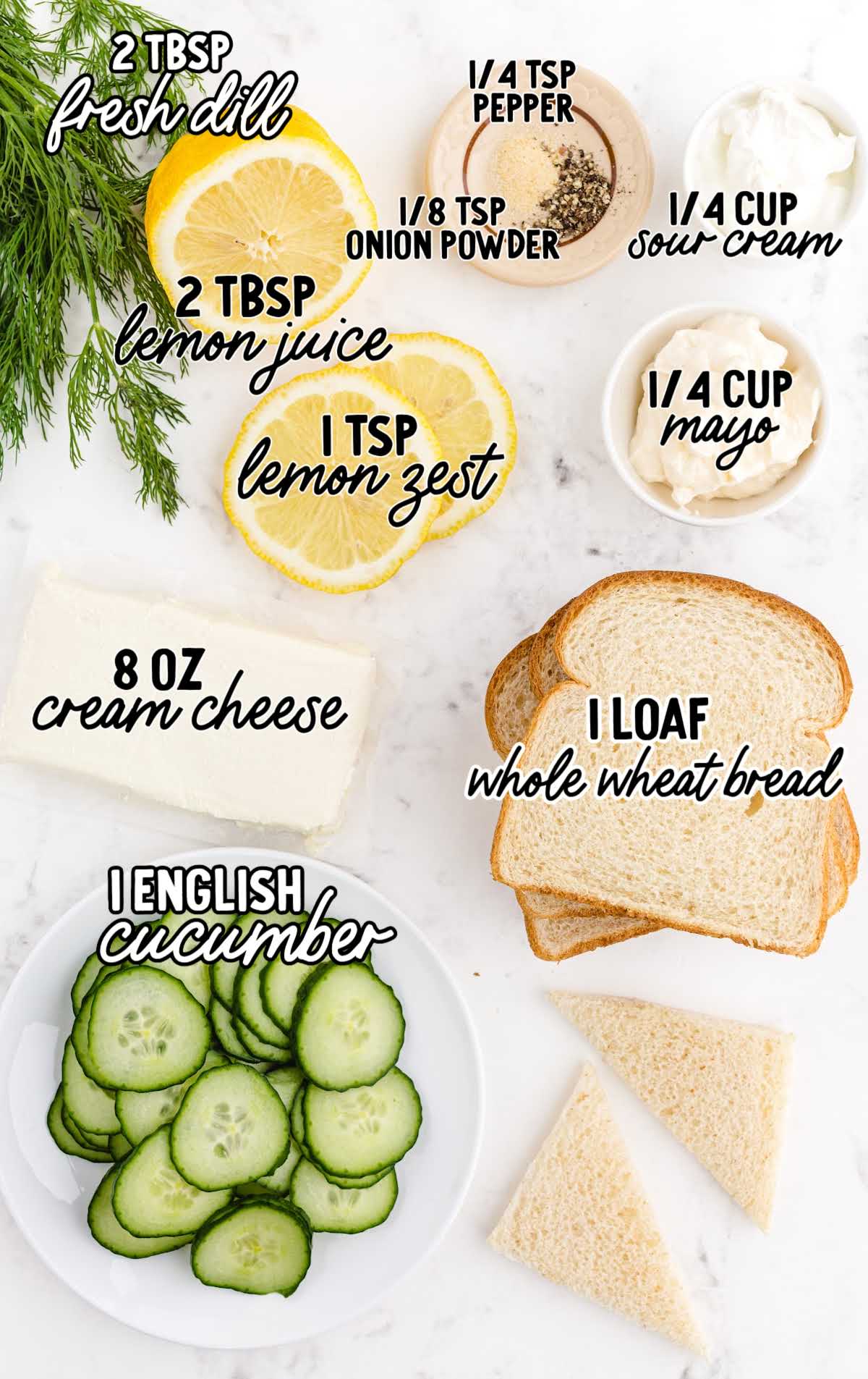 Flat lay of ingredients for cucumber sandwiches including cream cheese, fresh dill, lemon, seasonings, cucumber slices, and bread.