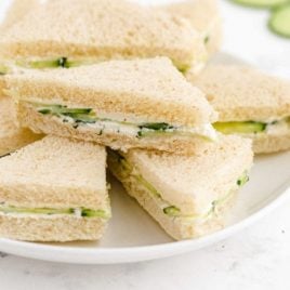 close up shot of cucumber sandwiches piled on top of each other on a plate