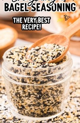 close up shot of everything bagel seasoning in a clear jar with a wooden spoon
