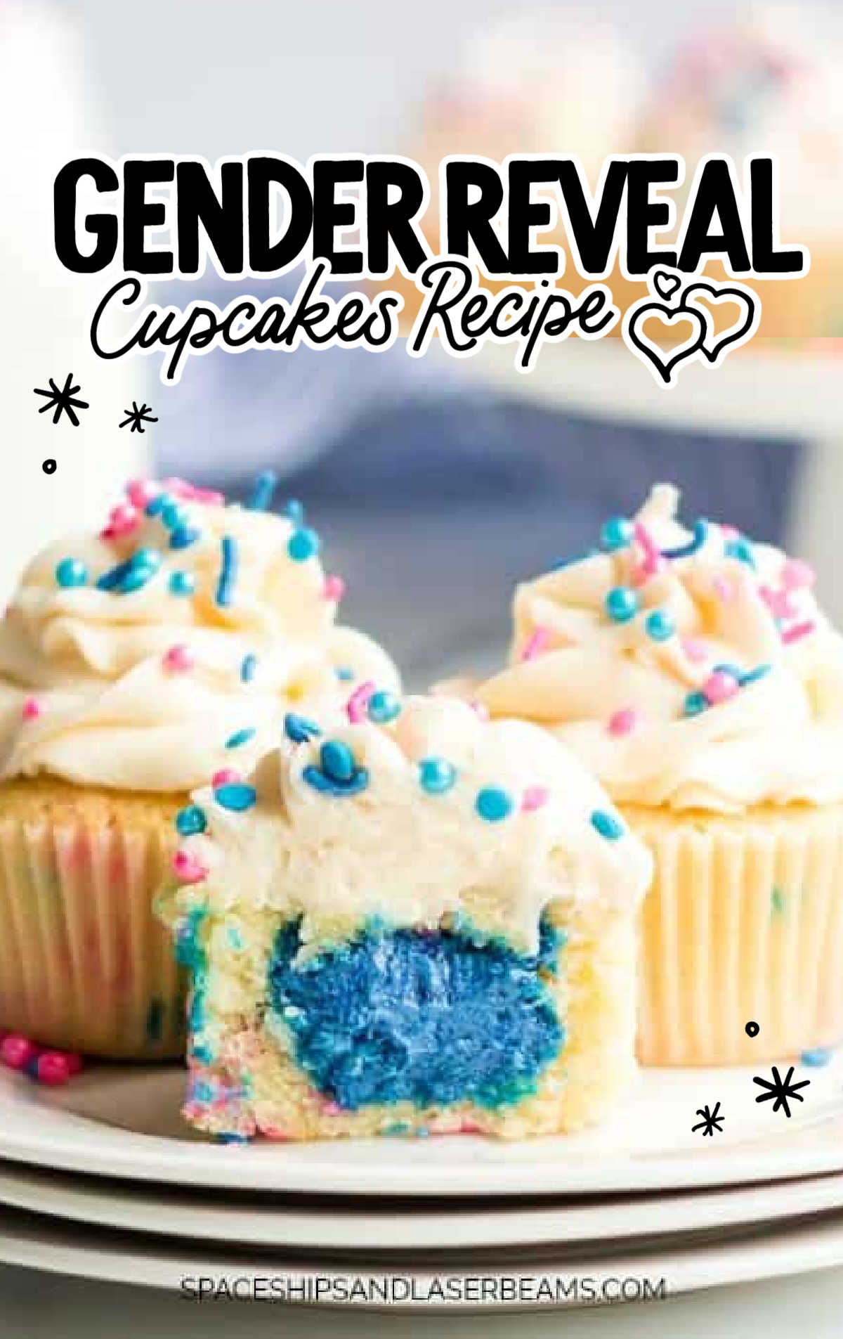 Vanilla cupcakes with fluffy buttercream frosting and pink and blue sprinkles, with a center filled with pink frosting.