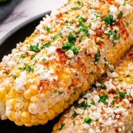 Mexican Corn on the Cob topped with parsley on a plate