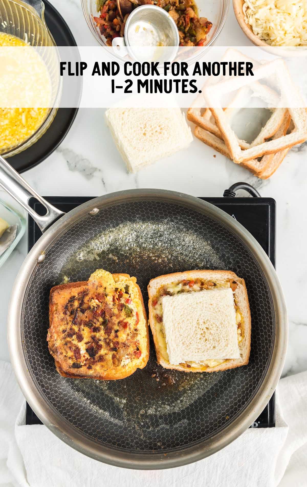 Cooking omelet toasts on a skillet, with one side browned and flipped.