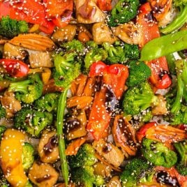 close up overhead shot of sheet pan stir fry topped with sesame seeds and sauce