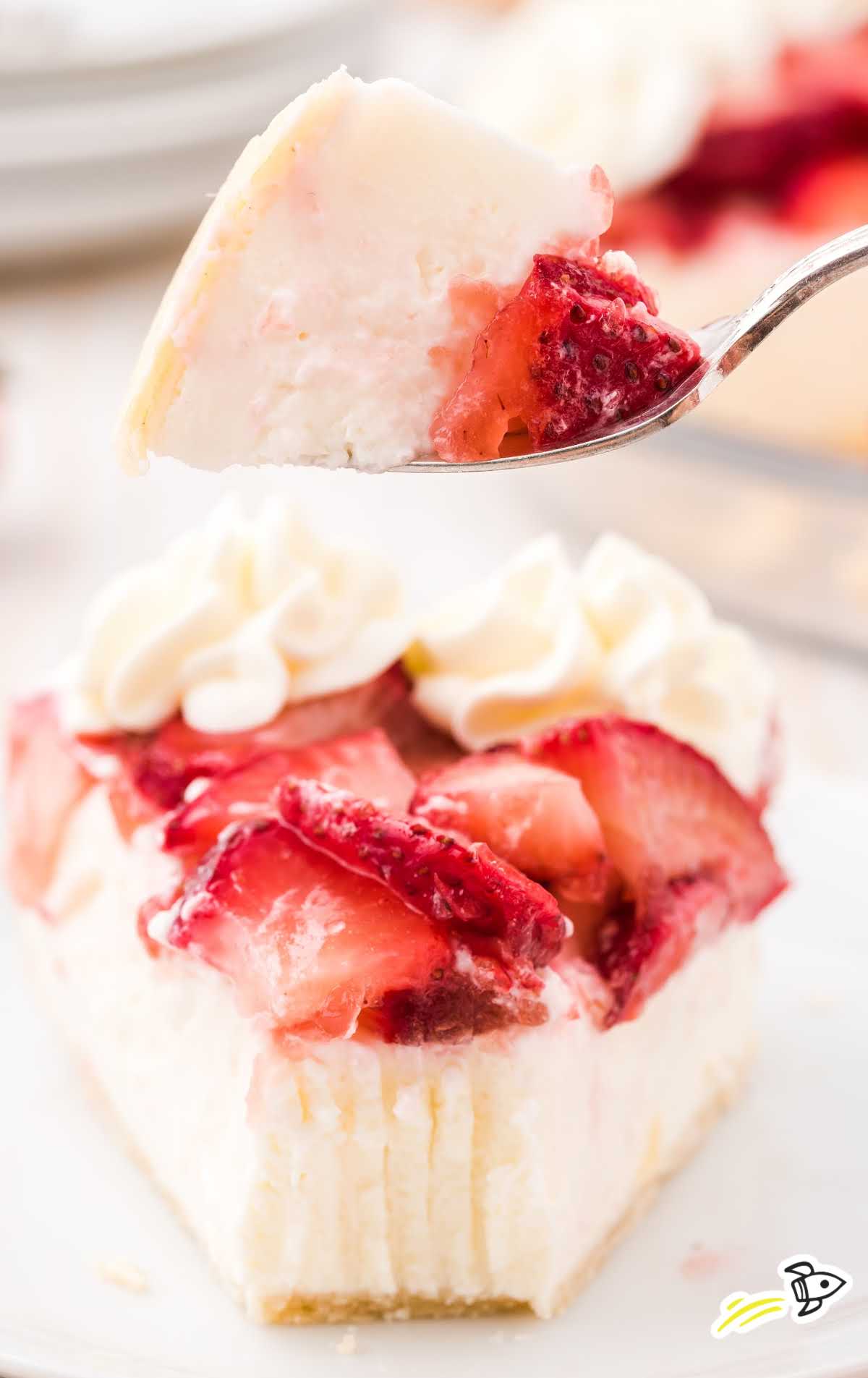 close up shot of a slice of strawberry cream cheese pie with sliced strawberries and a whipped topping