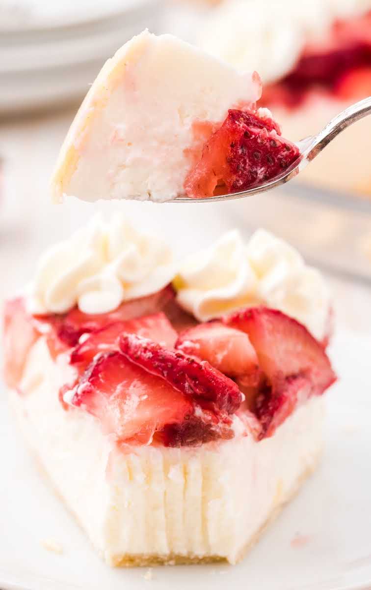 close up shot of a slice of strawberry cream cheese pie with sliced strawberries and a whipped topping