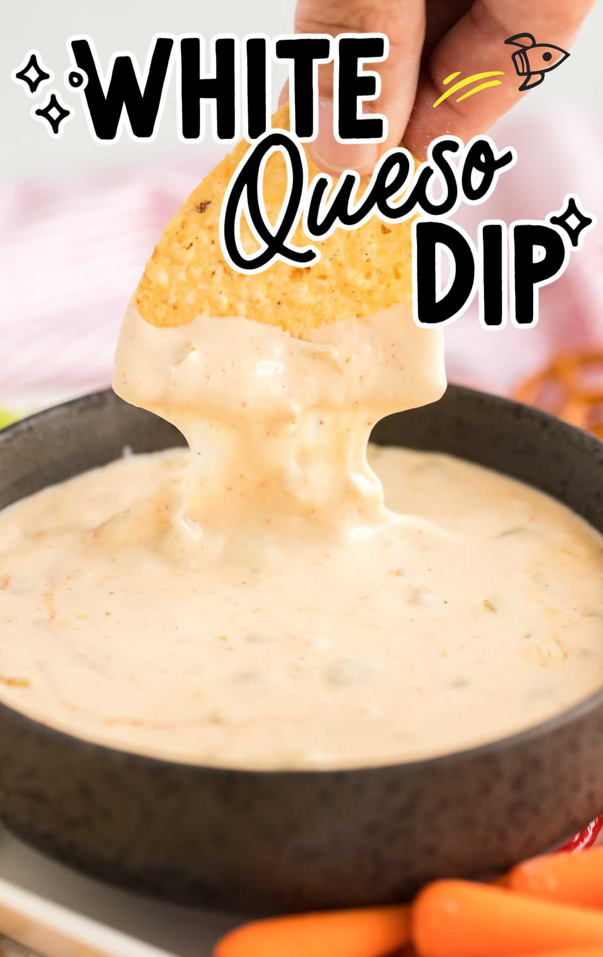 close up shot of a tortilla chip being dipped into a bowl of white queso dip