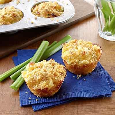 mini mac and cheese made in a muffin pan sitting on a blue napkin with celery sticks