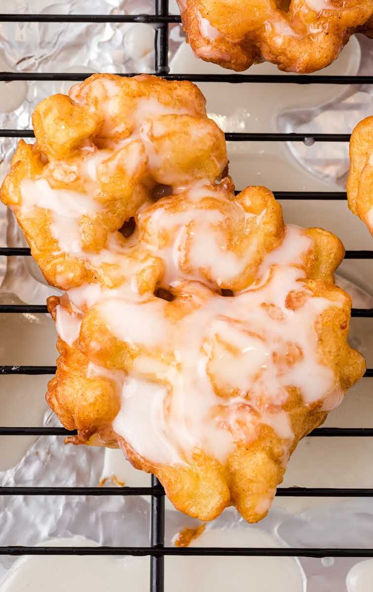 close up overhead shot of apple fritter recipe topped with a glaze on a cooling rack