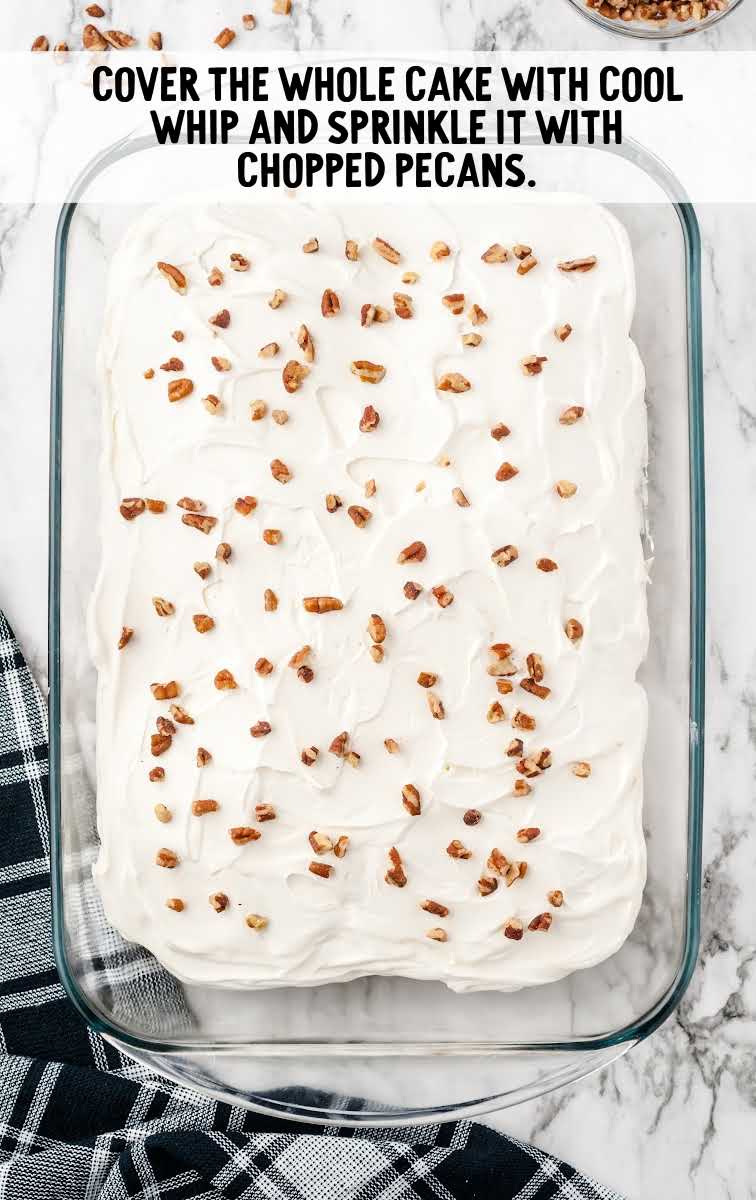 whipped cream being spread on top of cake and topped with pecans