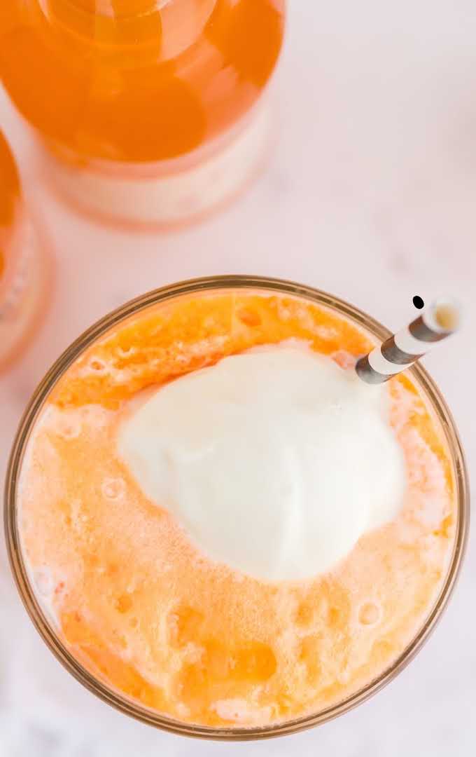 close up overhead shot of a glass of boozy creamsicle float with a straw