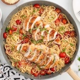 a skillet of bruschetta chicken pasta garnished with basil