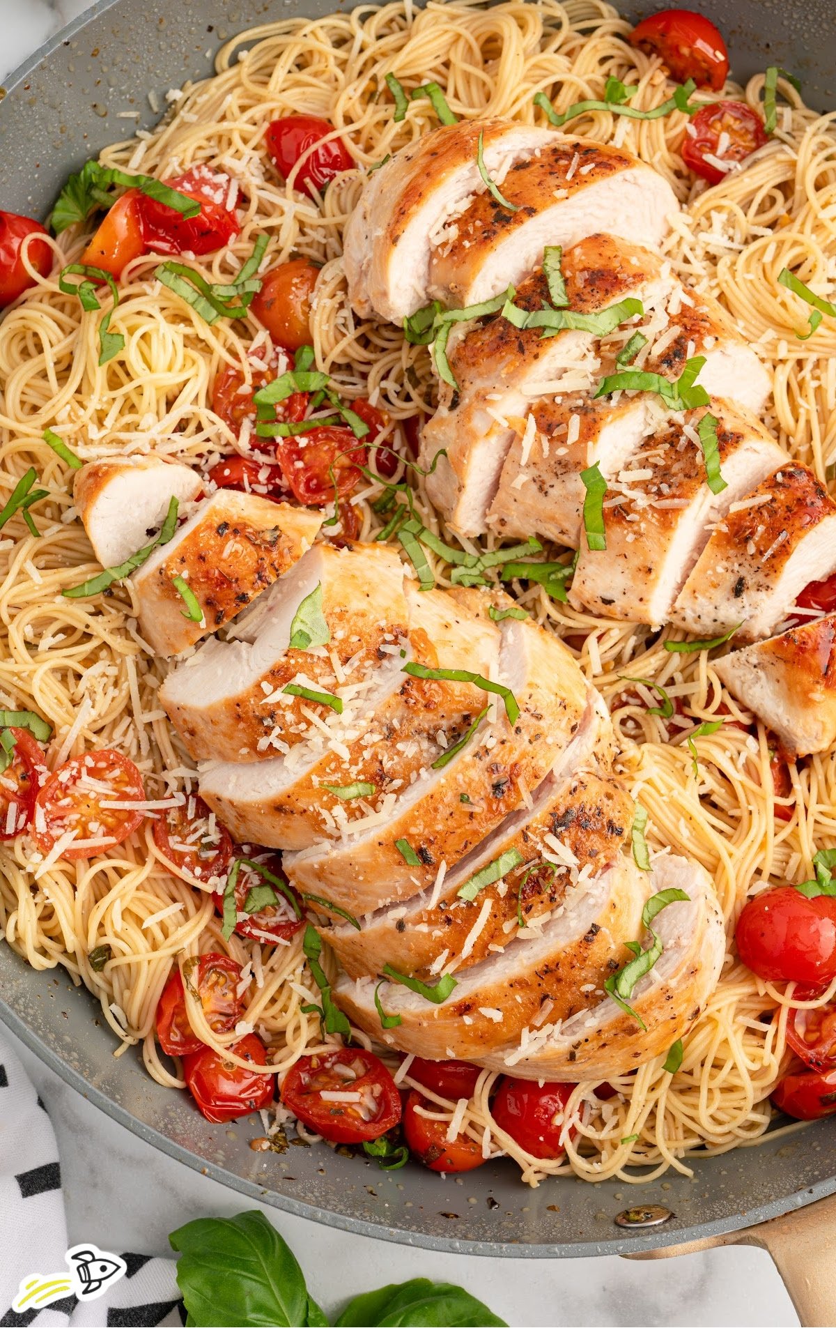 a skillet of bruschetta chicken pasta garnished with basil