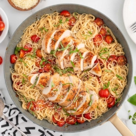 a skillet of bruschetta chicken pasta garnished with basil