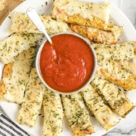 close up overhead shot of a plate of Cauliflower Breadsticks with a bowl of marina sauce