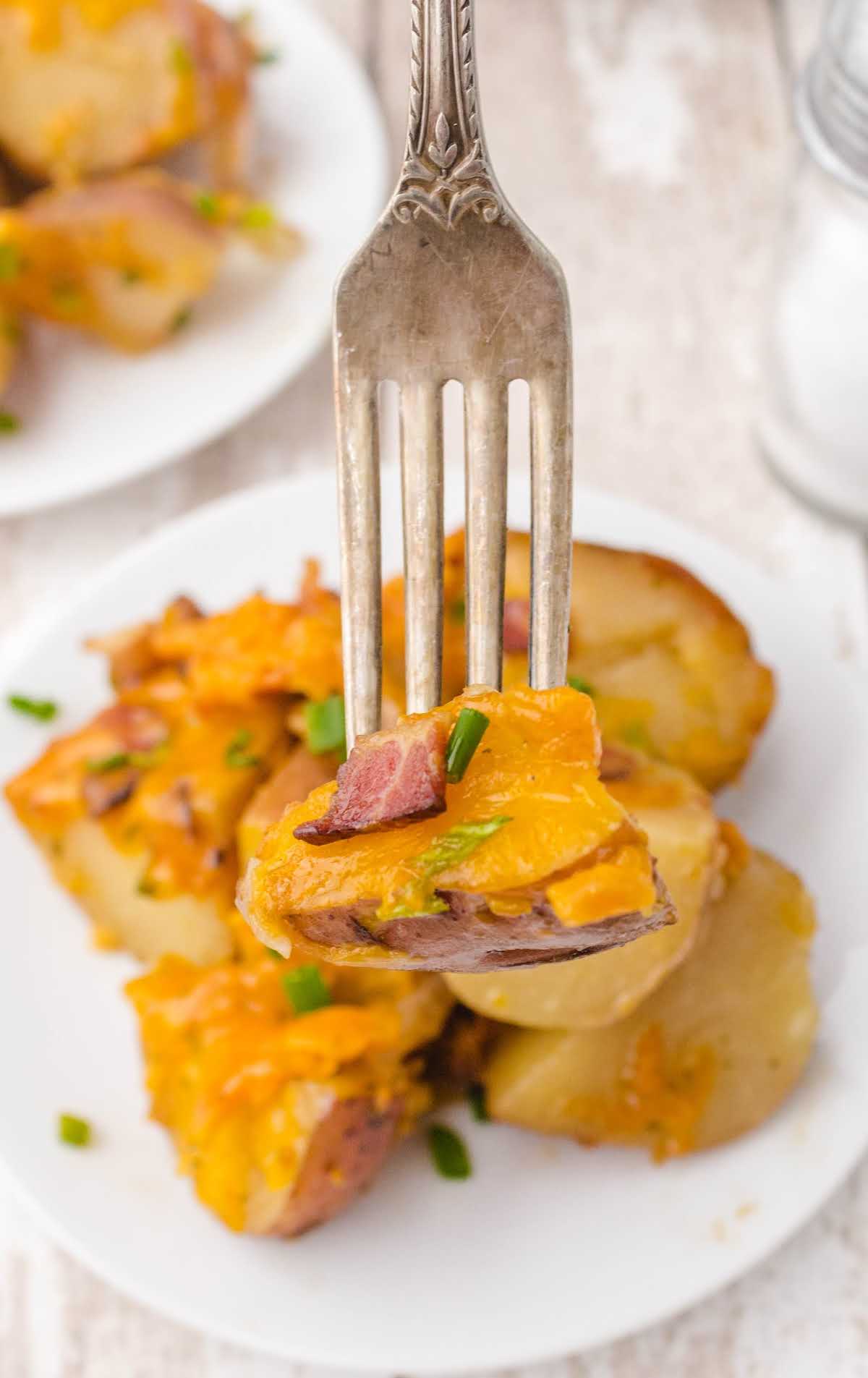 Cheesy Bacon Ranch Potatoes on a plate with a bite of potatoes a fork