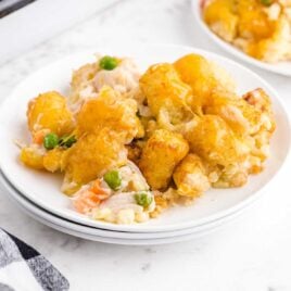 close up shot of a serving of chicken pot pie with tater tots on a plate with a fork