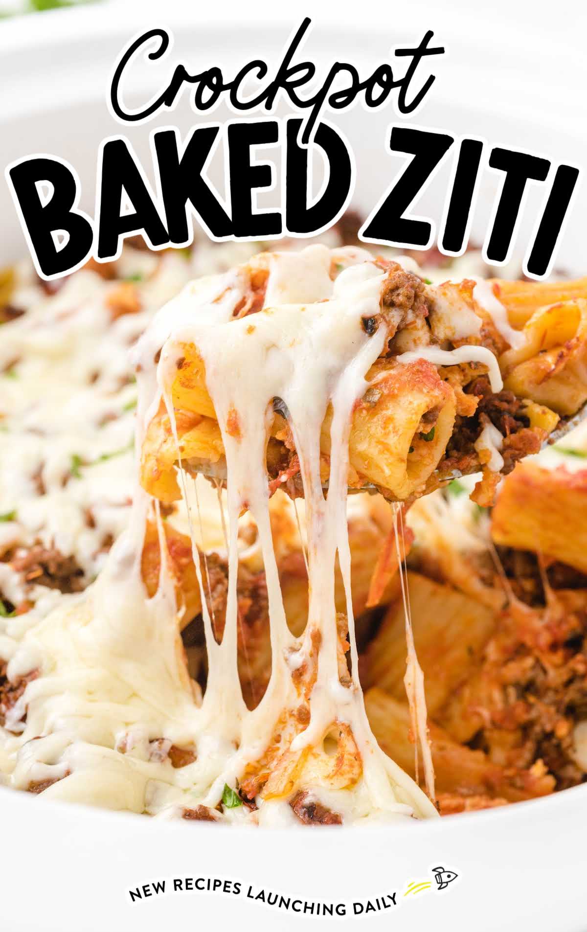 Close-up of a serving spoon lifting cheesy baked ziti from a crockpot.