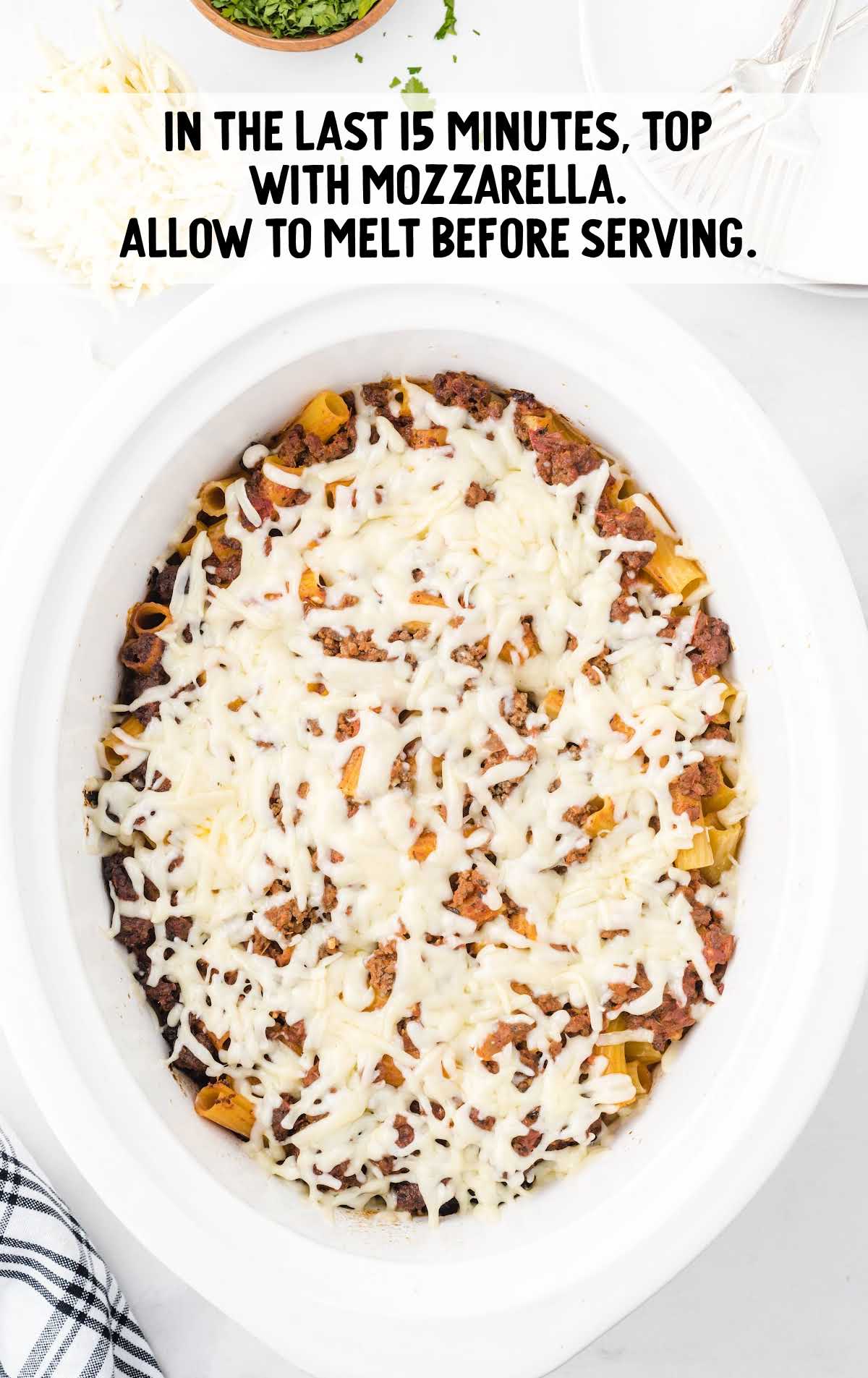 Crockpot baked ziti topped with melted mozzarella in the final cooking stage, ready to serve.