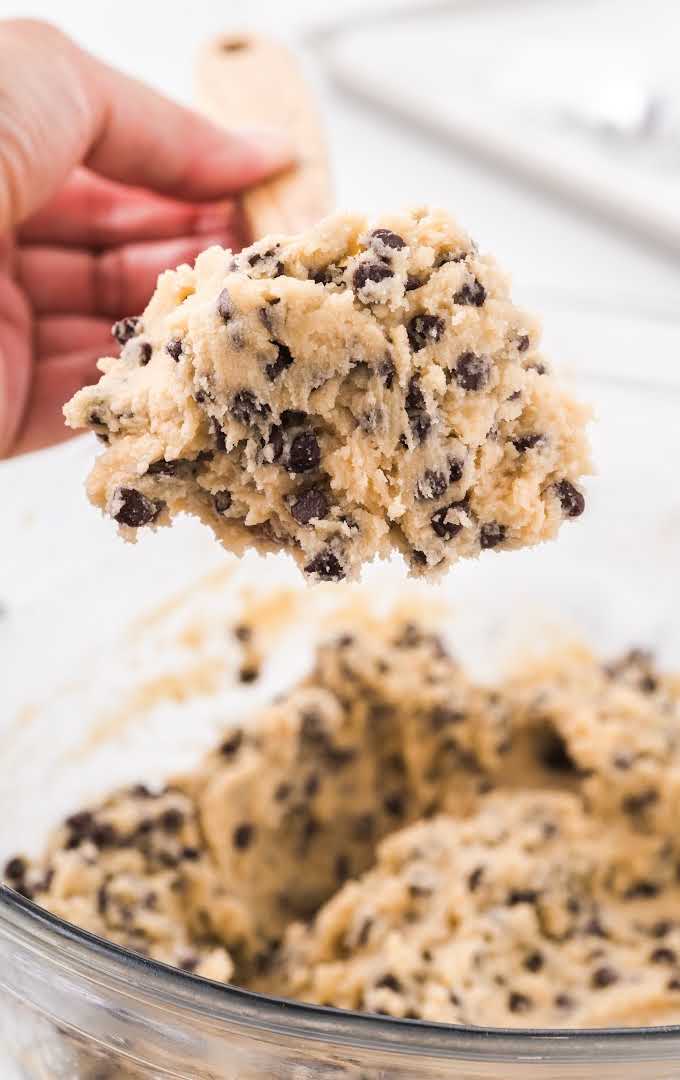 close up shot of edible cookie dough on a large wooden spoon