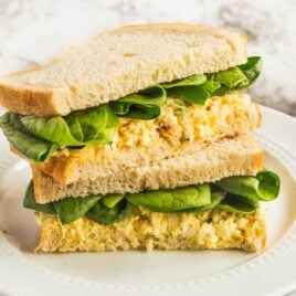 close up shot of Egg Salad Sandwich stacked on top of each other on a plate