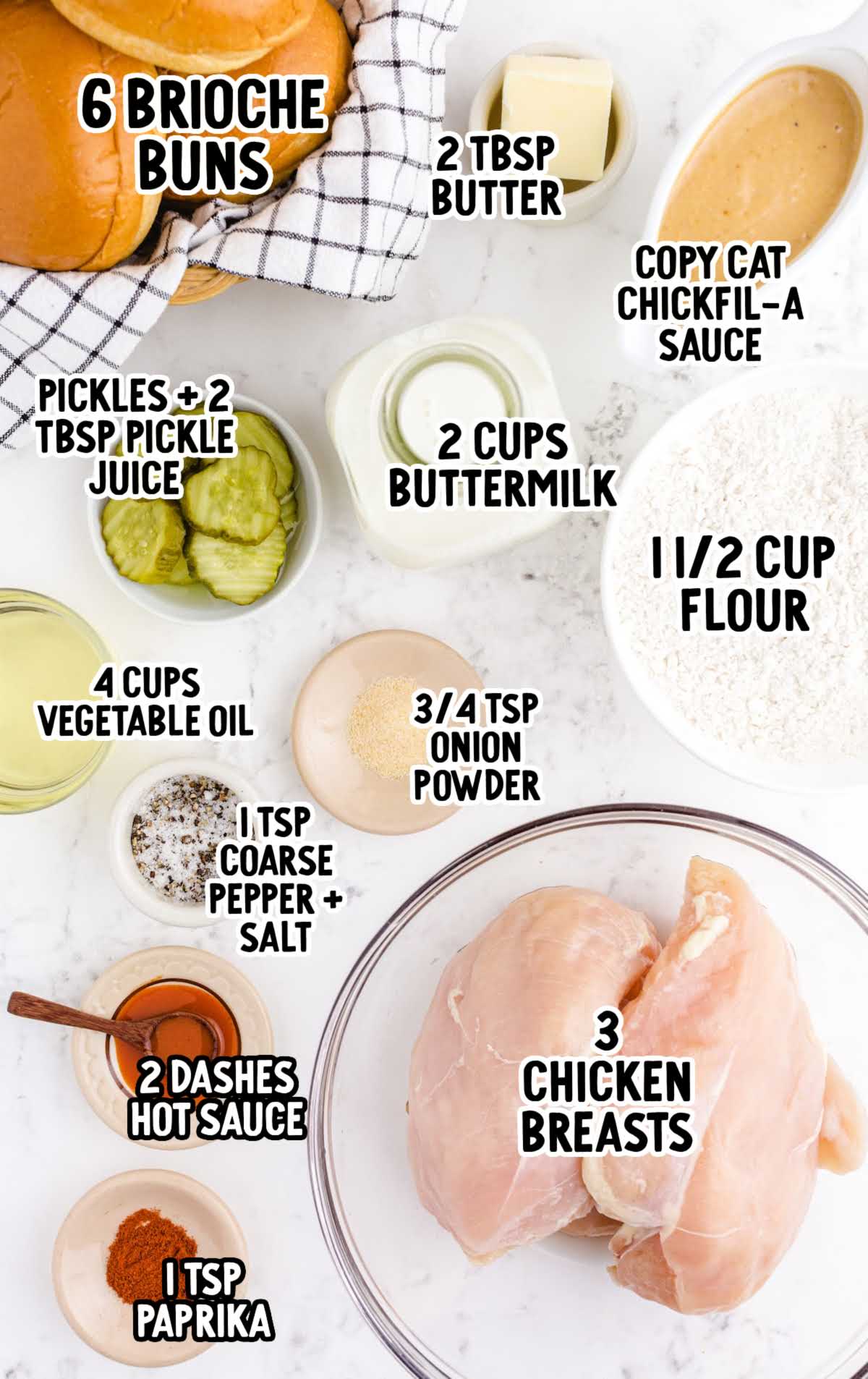 Flat lay of ingredients for fried chicken sandwiches, including brioche buns, chicken breasts, spices, buttermilk, flour, pickles, and sauce, each labeled with text