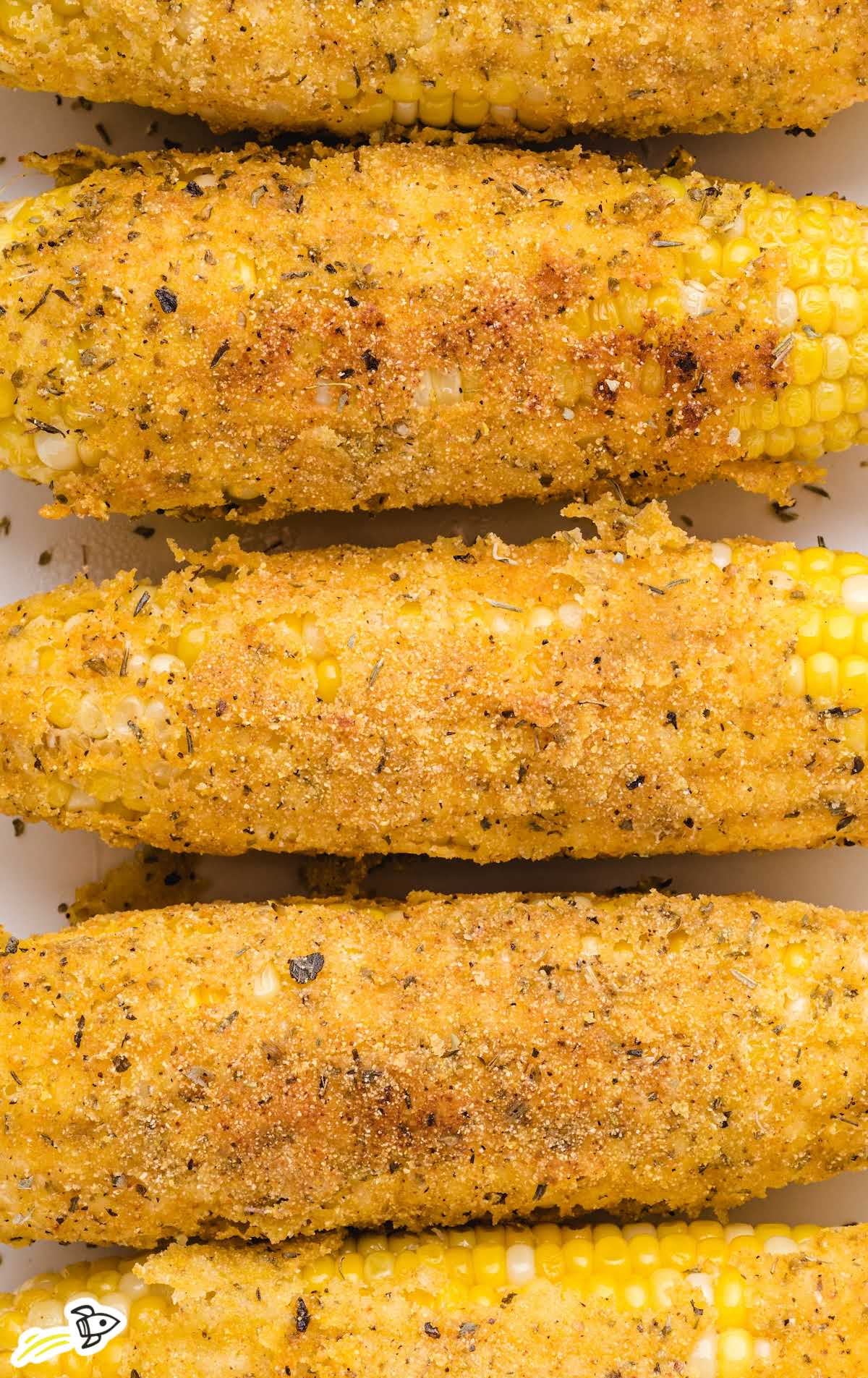 Fried corn on the cob being cooked in oil in a cast iron skillet and served on a plate