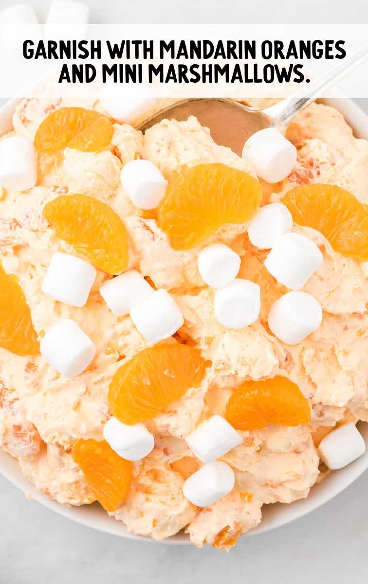 orange creamsicle salad process shot of salad being topped with mandarin oranges and mini marshmallows