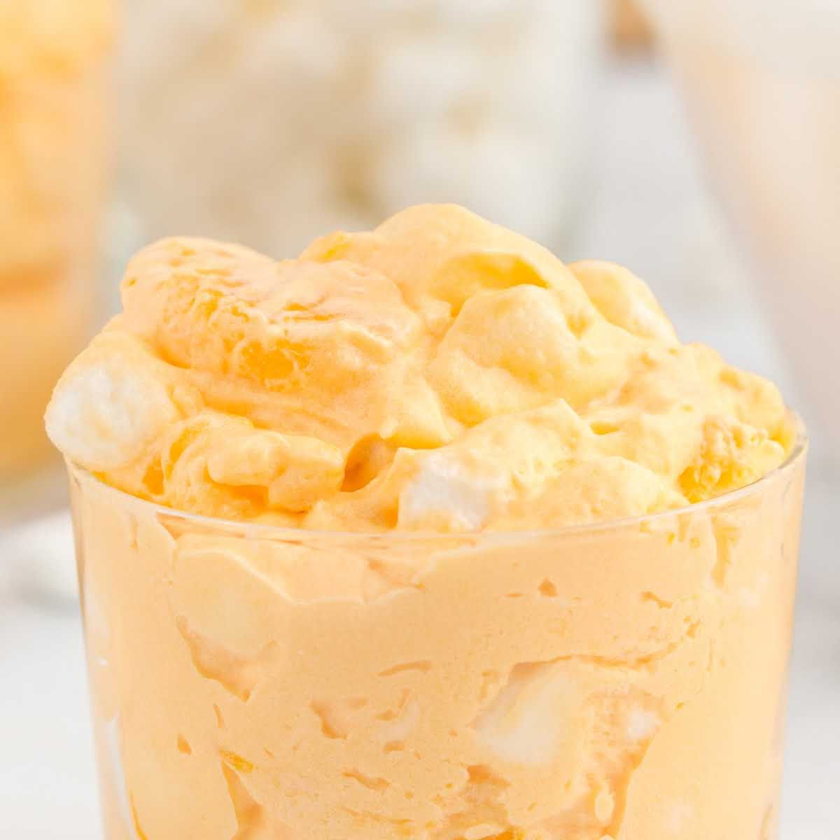 a cup of Orange Fluff topped with marshmallows and orange slices