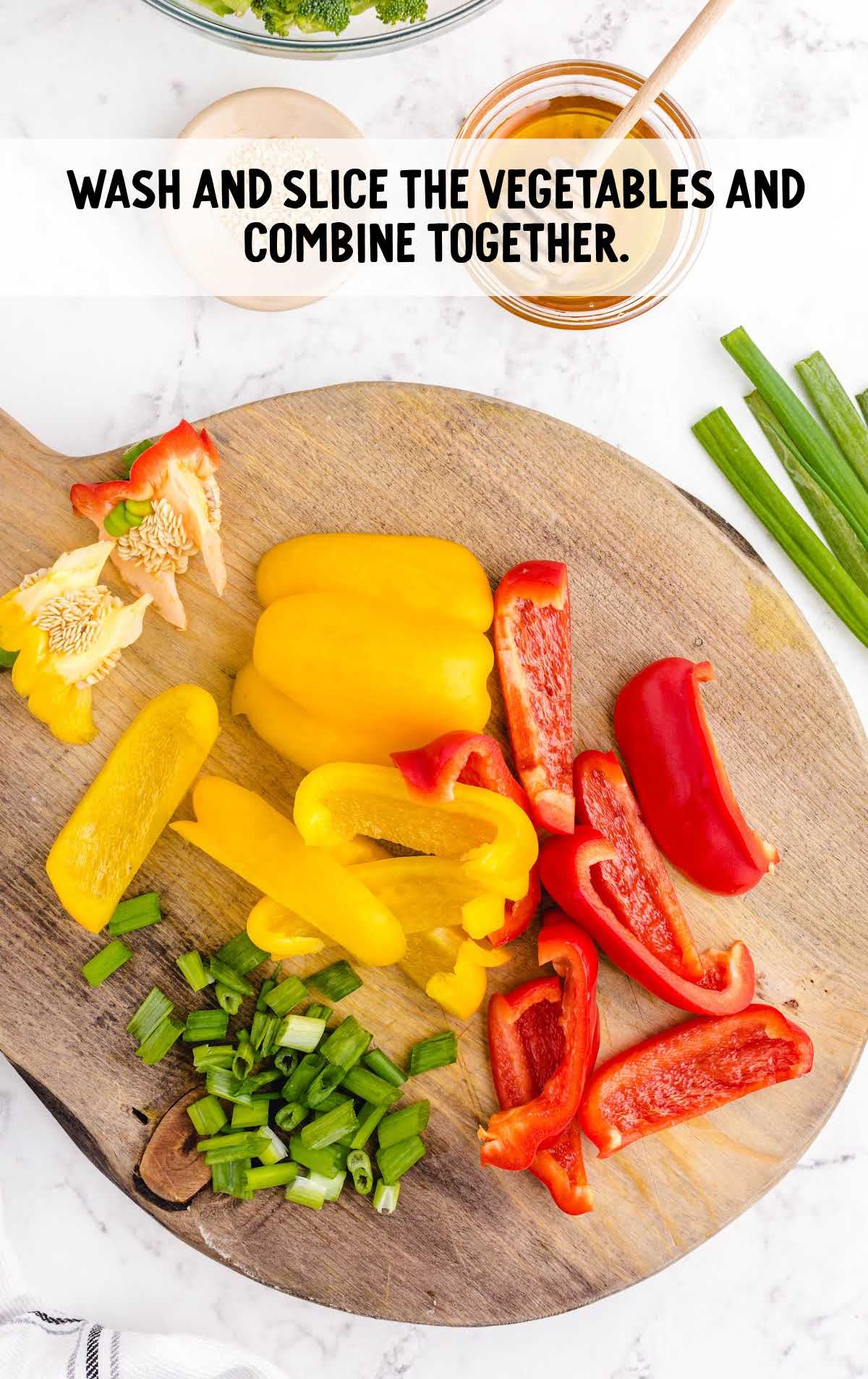 Chopped yellow and red bell peppers and green onions on a cutting board ready for the stir fry.