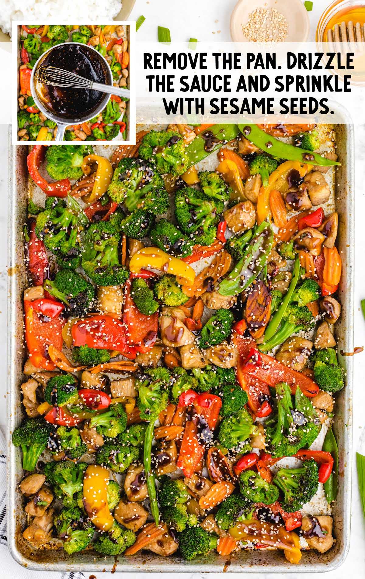 Cooked stir fry on a sheet pan with sauce drizzled and sesame seeds sprinkled on top, ready to serve.
