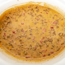 White crockpot filled with warm, cheesy beef Rotel dip.