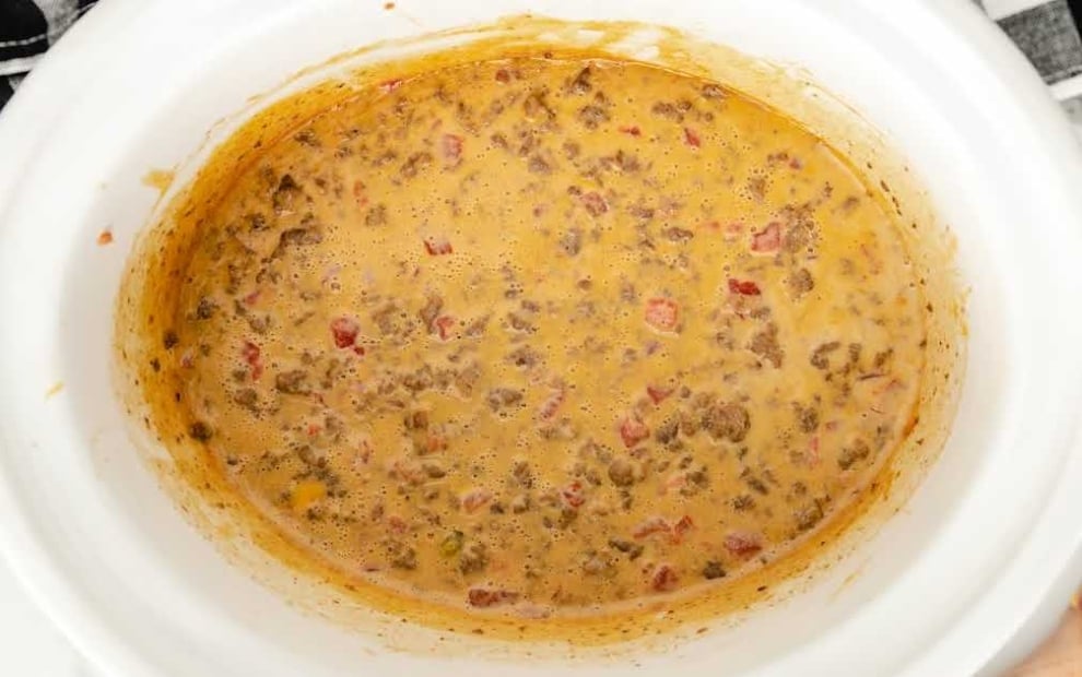 White crockpot filled with warm, cheesy beef Rotel dip.