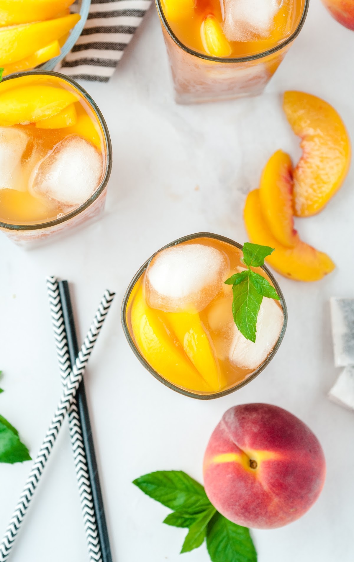 overhead shot of a tall glass of Sweet Peach Iced Tea served with peaches