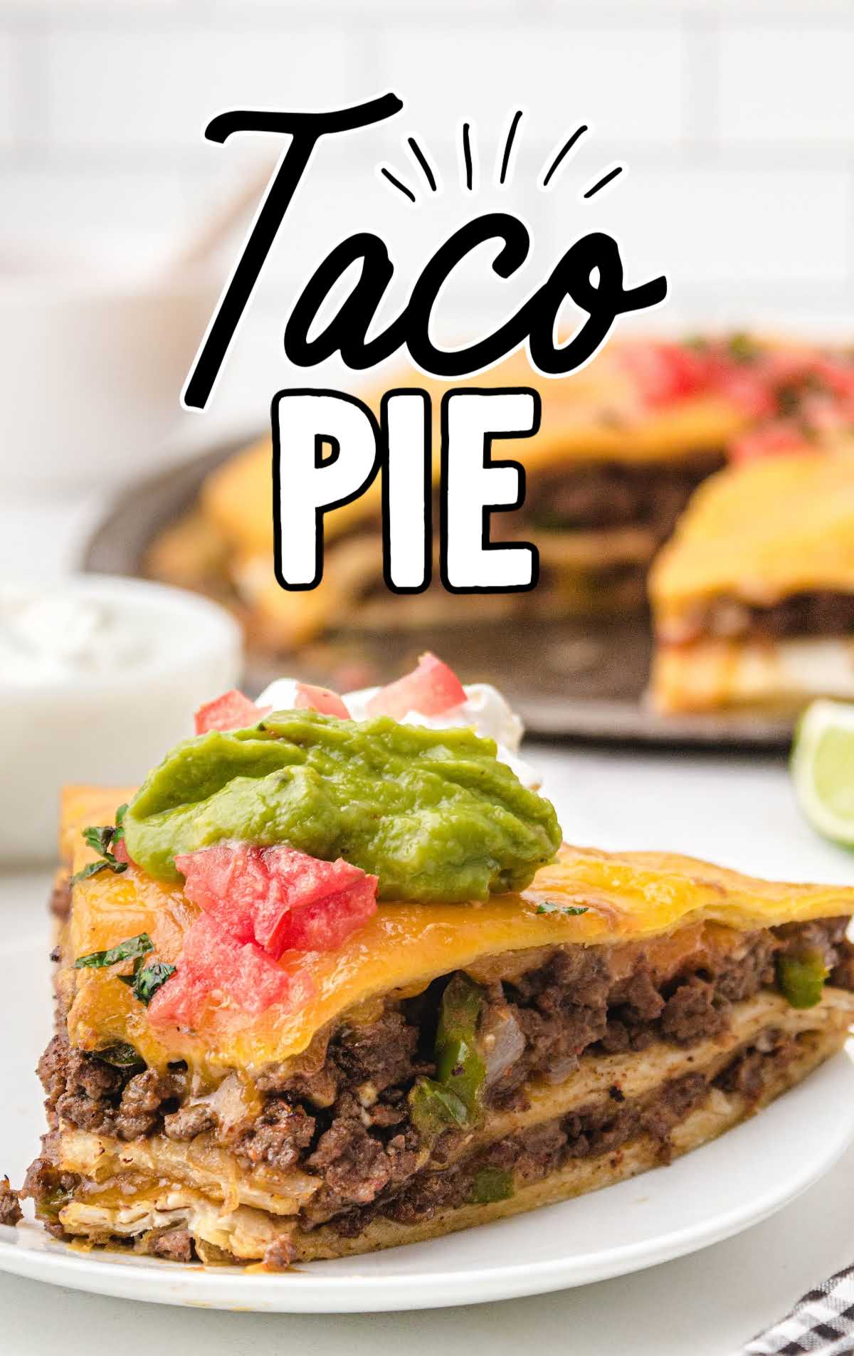 a slice of taco pie topped with tomato slices, guacamole, sour cream, and cilantro on a plate