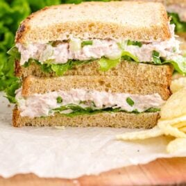 close up shot of the layers of tuna sandwich stacked on top of each other with potato chips