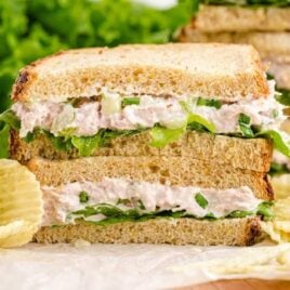 close up shot of the layers of tuna sandwich stacked on top of each other with potato chips