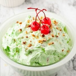 a bowl of Watergate Salad topped with pecans and cherries